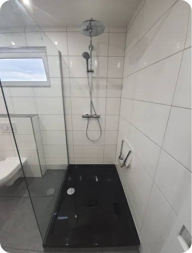 Dusche mit schwarzer Duschtasse und weißen Wandfliesen